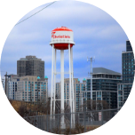 Large white metal structure on legs in Etobicoke, with buildings in the background.