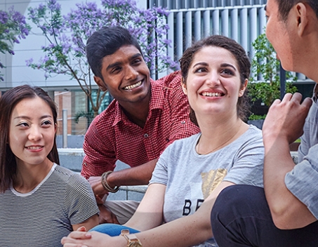 Group of four males and females, talking and smiling.