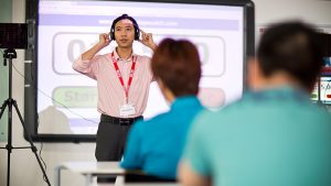 People in a classroom take the listening section of the IELTS People taking the listening section of the IELTS