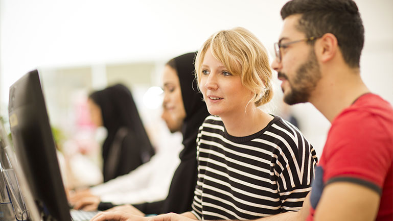 Two classmates study together in front of the computer. Two classmates work together on a computer.